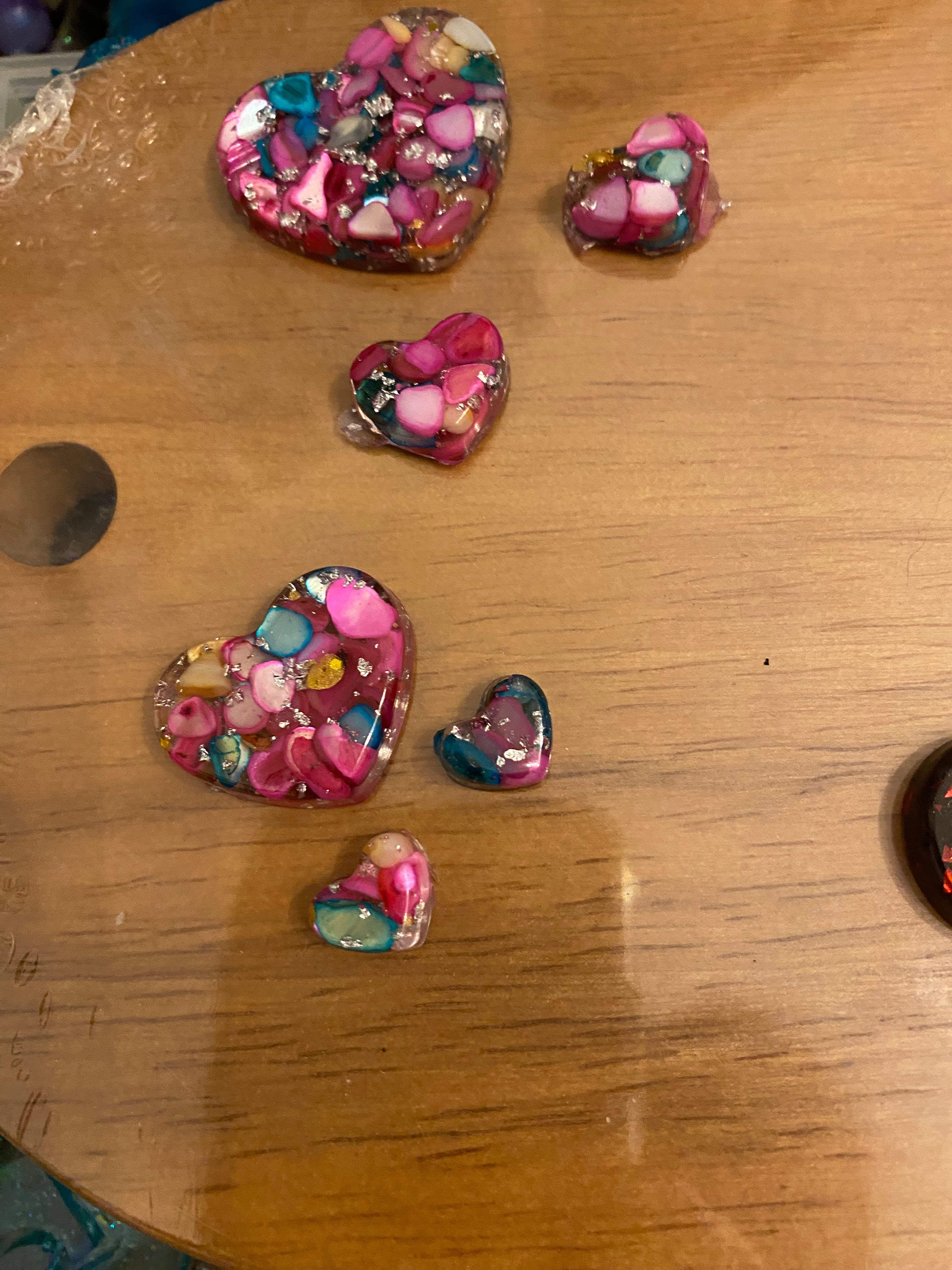 Love heart pendant and earring set featuring colorful resin hearts in various sizes on a wooden surface.