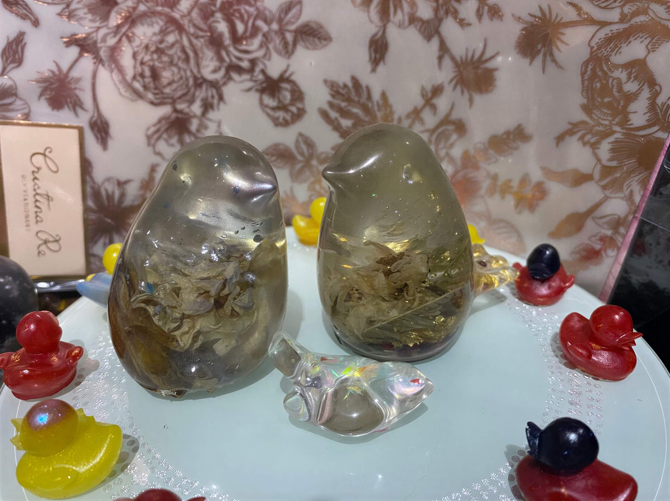 Two resin bird figurines with floral details, surrounded by colorful candy shapes on a decorative plate.