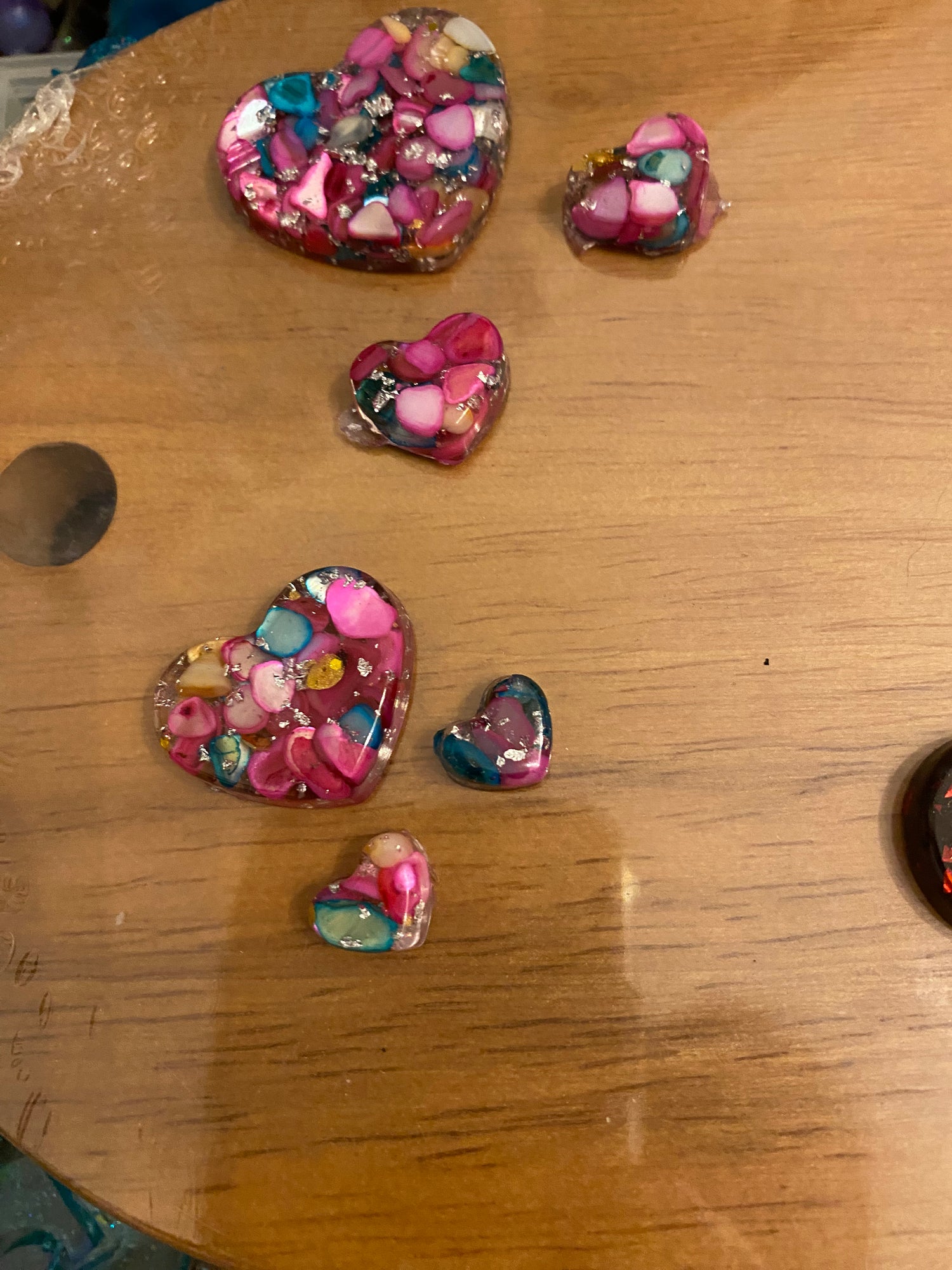 Love heart pendant and earring set featuring colorful resin hearts in various sizes on a wooden surface.