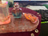 Colorful bathroom set featuring decorative glass bottles in blue and pink, displayed on a clear tray with glitter accents.