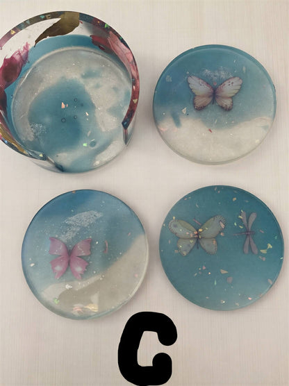 Coaster set featuring four round coasters with butterfly designs in blue and white resin.