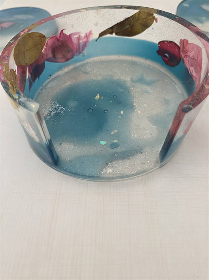 Clear coaster set with blue resin, featuring dried flowers and glitter embedded in the design.
