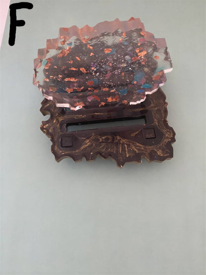Coaster set with a clear, textured top and a decorative black stand, featuring colorful specks embedded in the surface.