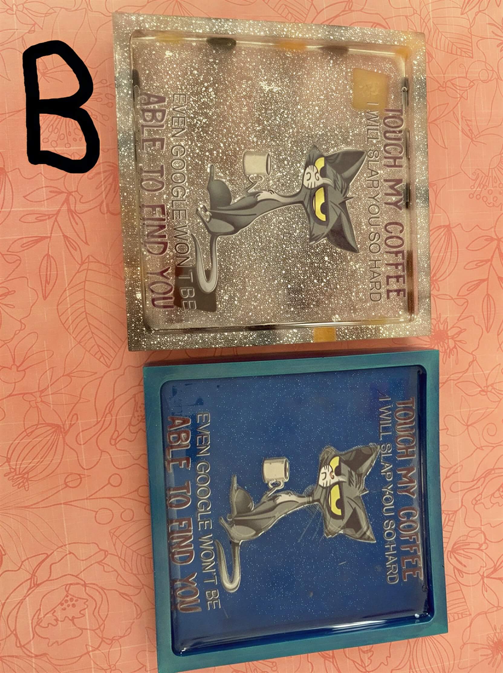 Two rectangular coasters with humorous text, one in blue and one with a glittery finish, featuring cartoon characters.