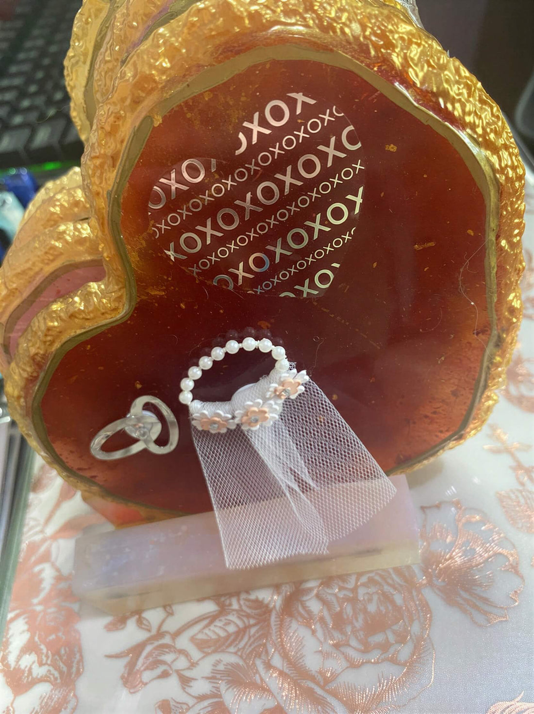 Heart-shaped wedding coasters with gold edges, featuring a decorative ring and small veil on a light surface.