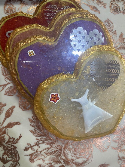 Heart-shaped wedding coasters in purple, red, and clear with decorative elements like a dress and flowers.
