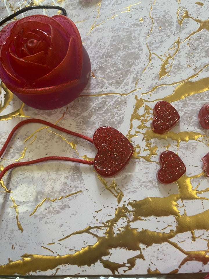 Red heart-shaped set featuring three small glittery hearts and a larger rose-shaped piece on a textured gold and white bac...