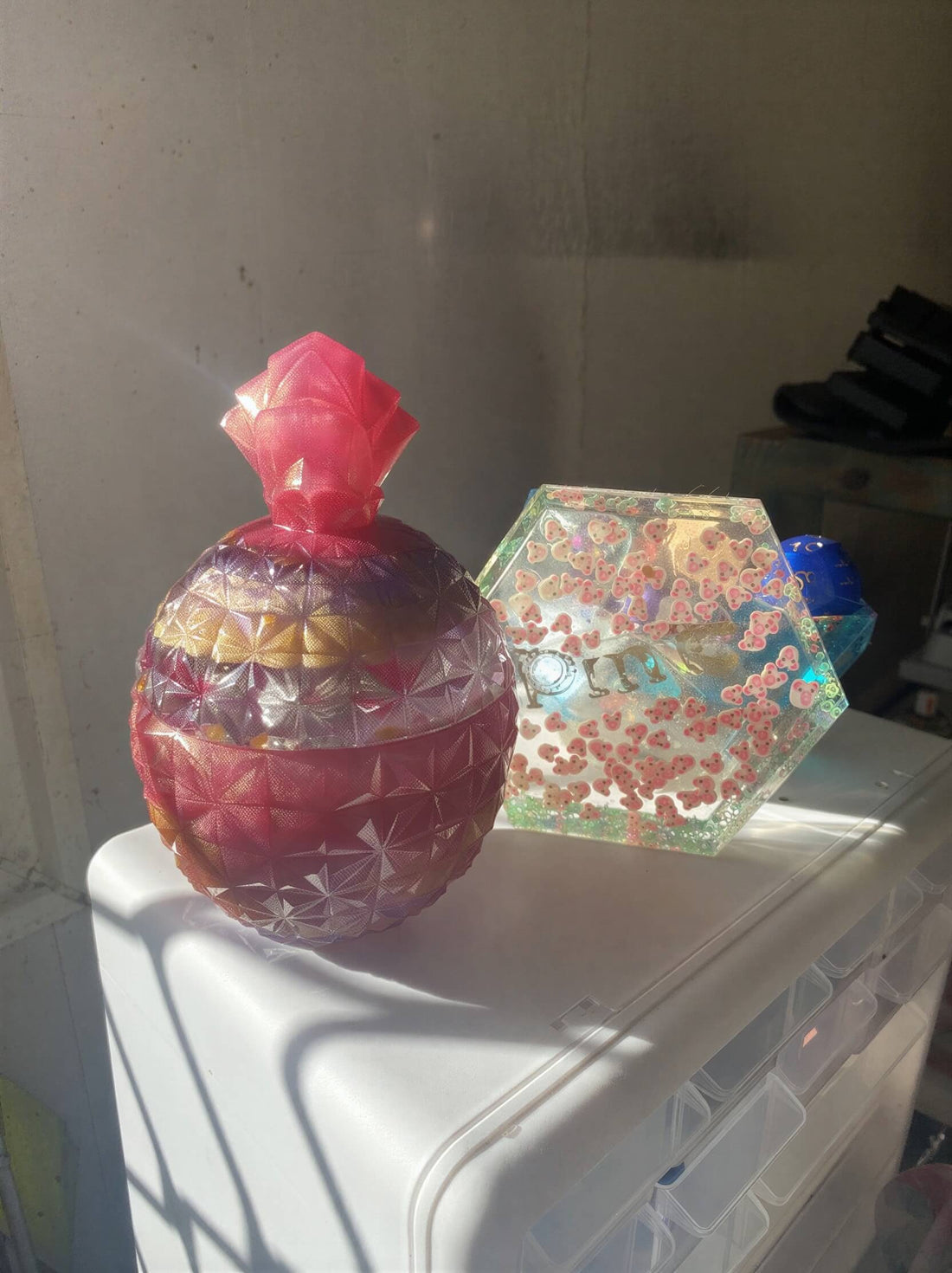Large jar with a colorful rose design in pink, purple, and gold, next to a hexagonal jar with floral patterns.