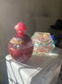 Large jar with a colorful rose design in pink, purple, and gold, next to a hexagonal jar with floral patterns.