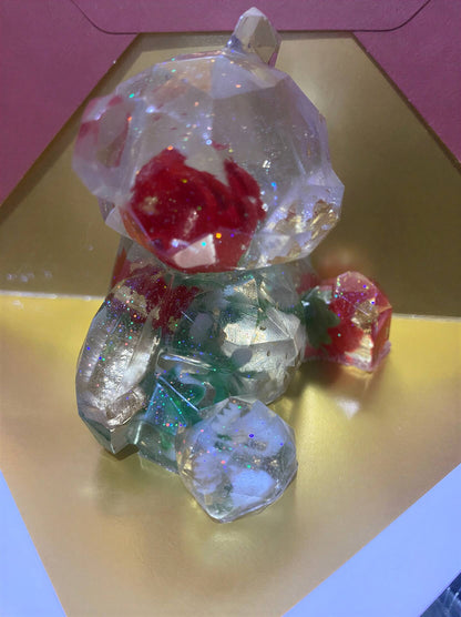 Crystal rose bear figurine with red and green accents, sitting on a gold background.